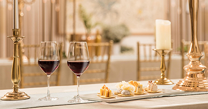 연회장 안에 기다란 테이블위에 와인을 즐길 수 있는 잔, 접시가 세팅되어 있다.