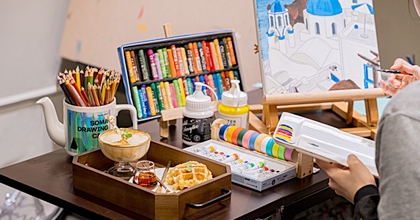 책상위에 밑그림이 그려진 캔버스와 색연필, 물감, 파스텔 등 갖은 그림도구들이 갖춰져 있다.